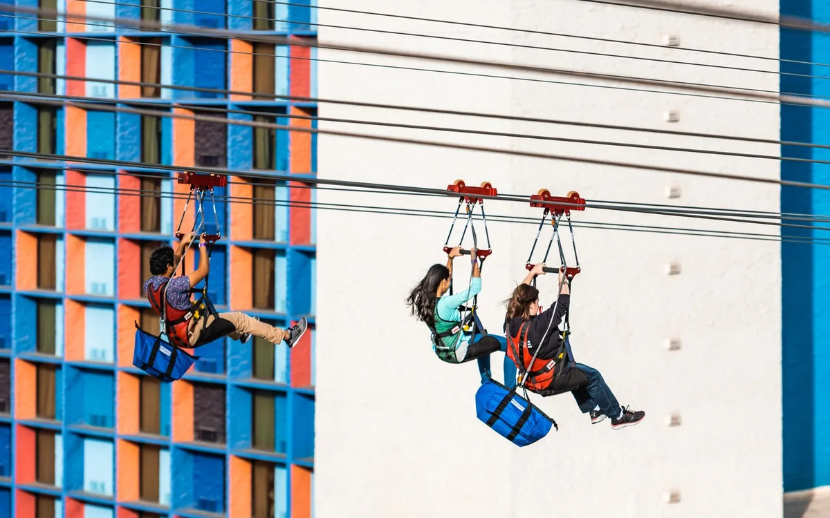 Two riders side by side on the zipline above the promenade
